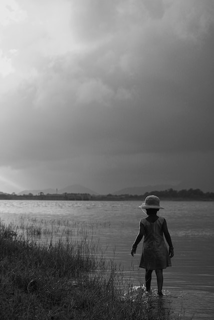 Child Walking Next To Lake During The Summer