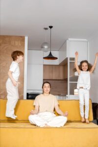 Woman Meditating With Two Kids On A Couch