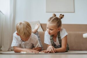 Two Kids Lying Down Doing Their Homework