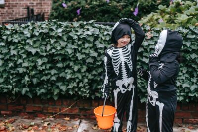 Two Children Trick-Or-Treating In their Skeleton Costumes