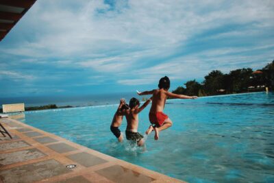 Three Children Jumping In A Pool