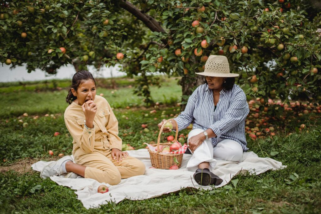 Family Having A Picnic In Apple Orchard