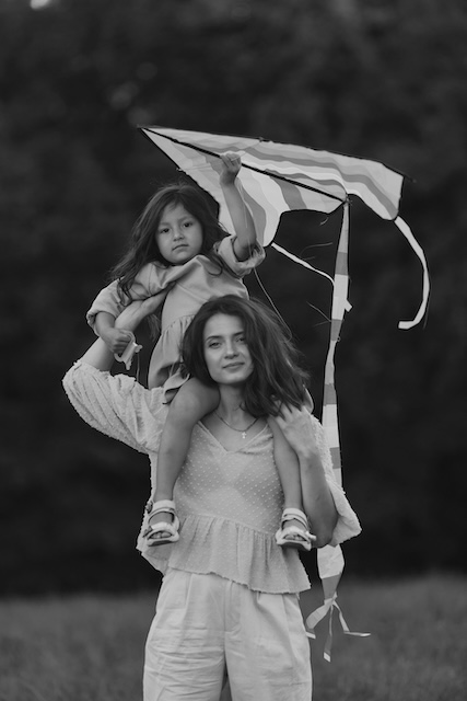 Child Sitting on Nanny's Shoulders Holding a Kite In London
