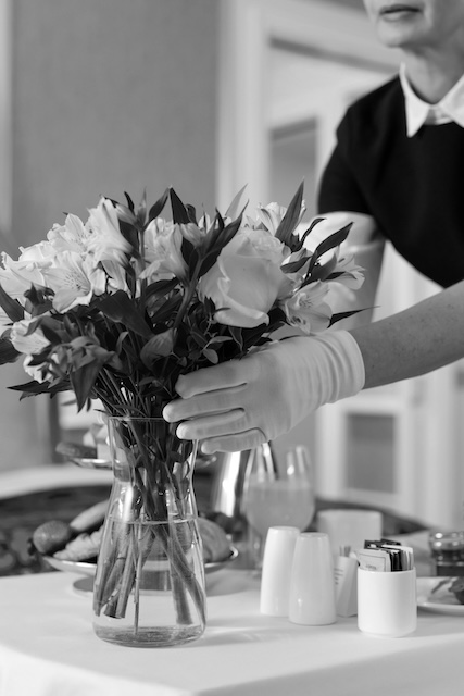 Housekeeper Arranging Flowers In A Vase