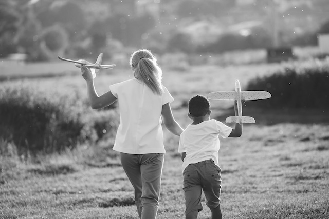 Nanny And Child Running Together Holding Toy Planes In Austin