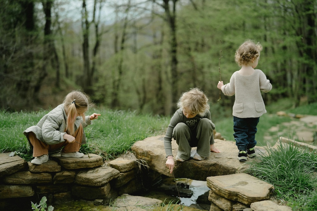 Children Exploring Creek With Sticks During Free Play