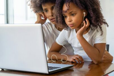 Child and Caregiver Wearing Headphones and Watching A Laptop Together