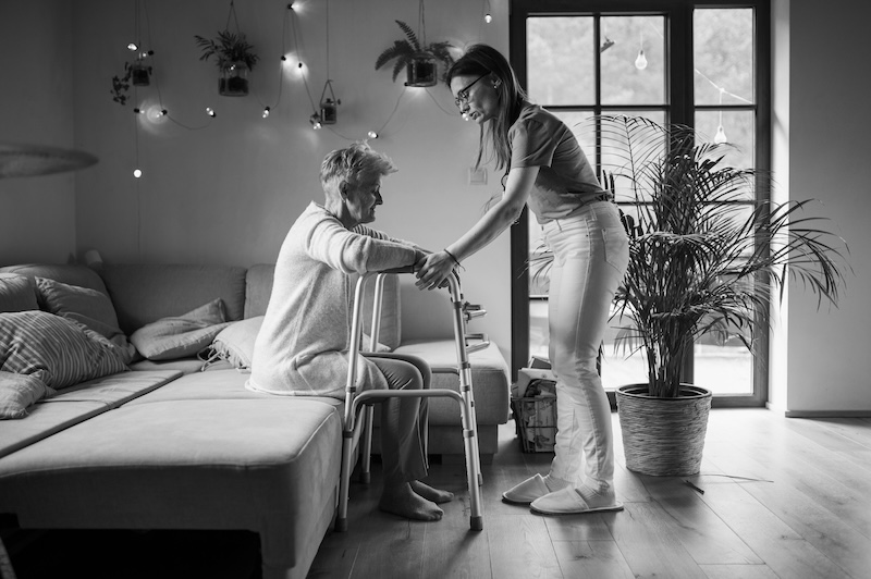 Caregiver Assisting Elderly Person Standing With Walker