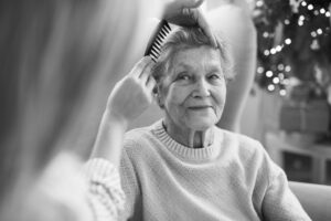 Caregiver Gently Brushing Elder Woman’s Hair