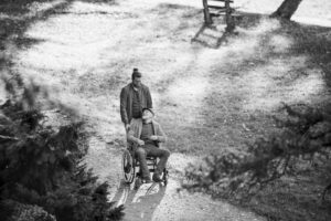 Caregiver Pushing Senior Man In Wheelchair As They Smile