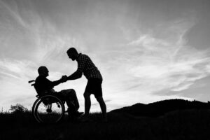 Caretaker Holding Hand Of Senior In Wheelchair Outdoors