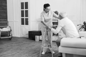 Registered Nurse Providing Mobility Assistance To Elder With Walker