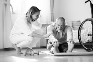 Senior Man Stretching With Caregiver Assistance