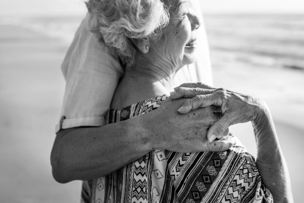 Smiling Elder With Caregiver On Beach